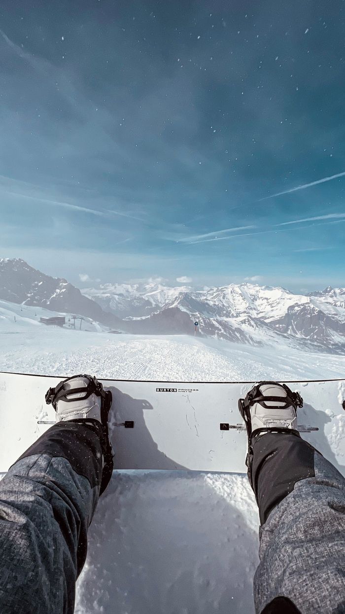 Mastering the First Impression: Your intriguing post title goes here Snowboarder's feet on a snowy slope with stunning Alpine mountain panorama.